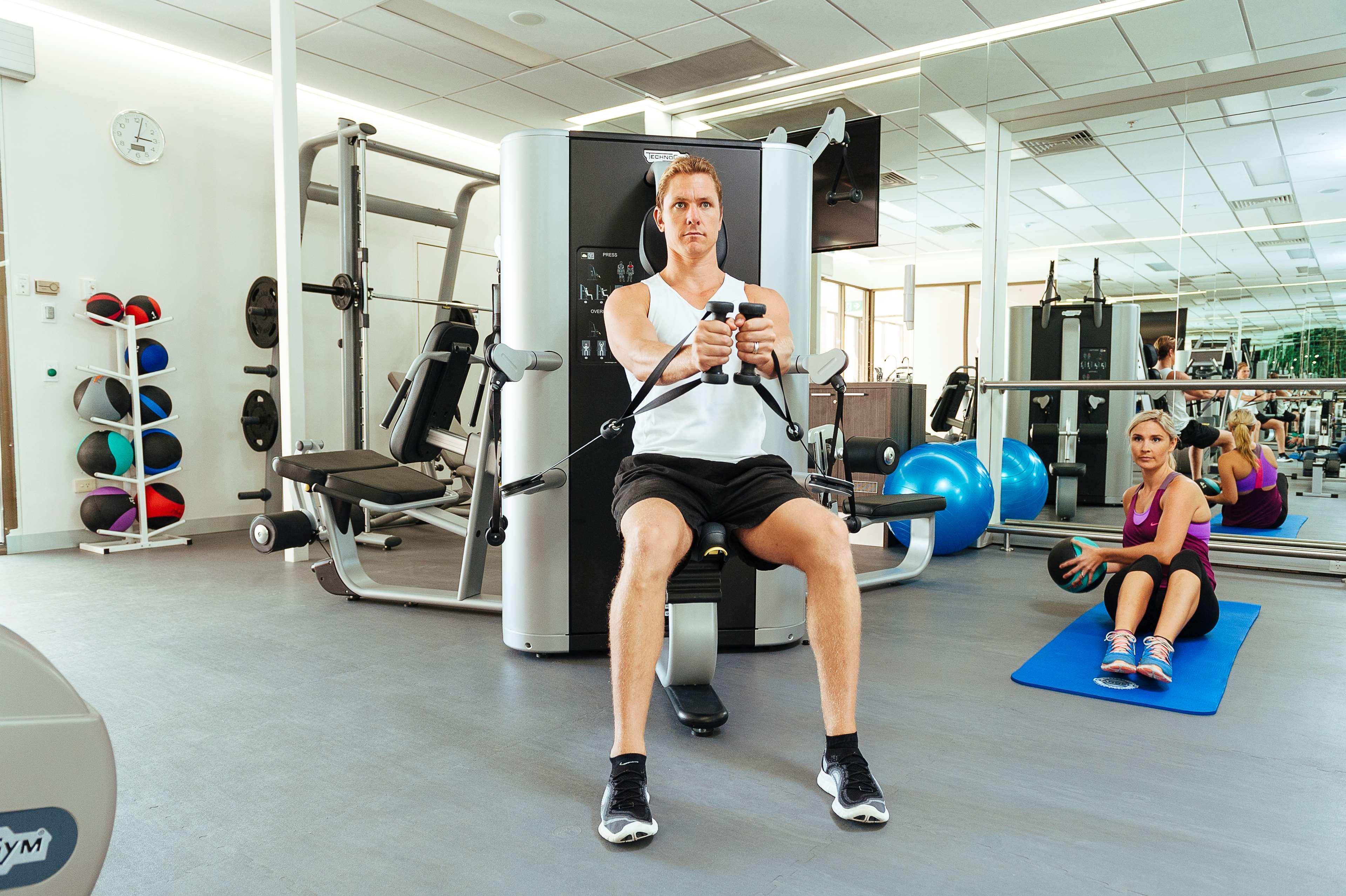 Stamford Plaza Adelaide Hotel Bagian luar foto The photo shows a gym setting with two individuals engaged in workout activities. 

In the foreground, a man is seated on a machine, using the handles to perform a rowing exercise. He is wearing a sleeveless shirt and shorts, indicating an active wor