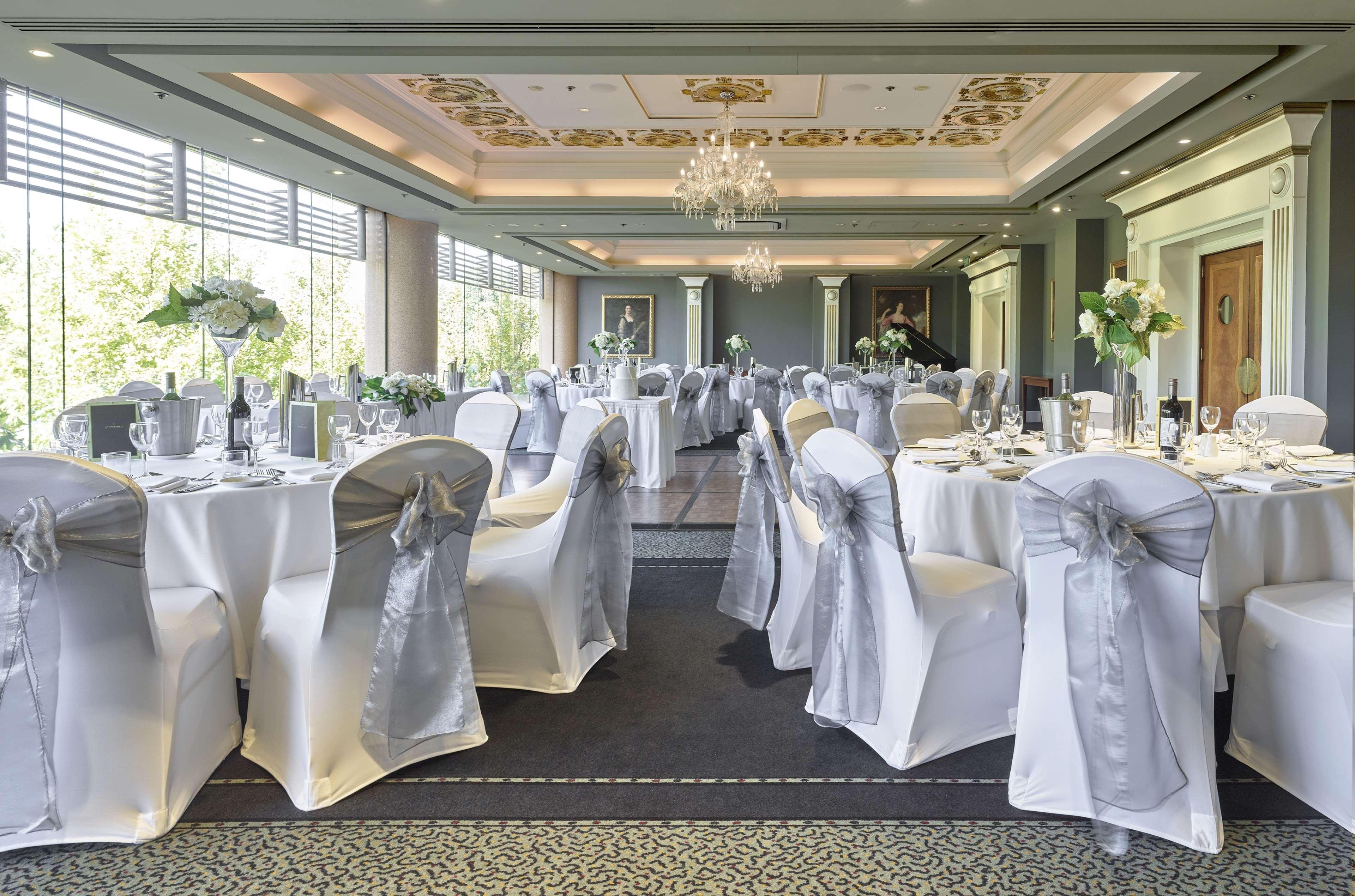 Stamford Plaza Adelaide Hotel Bagian luar foto The photo displays an elegantly arranged banquet hall. The room features several round tables covered with white tablecloths, each adorned with silver sashes on the chairs. There are floral centerpieces, possibly white flowers, on the tables, adding 